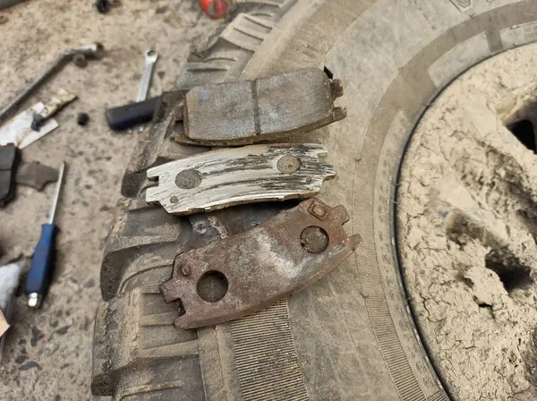 Yıpranmış fren pedleri araçtan çıkarılmış, sürtünme katmanındaki aşınma derecesi ve metal hasar açıkça görülüyor.