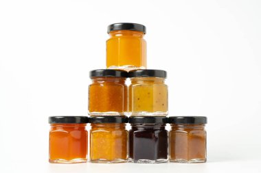 Reçel piramidi. Korsanlarda farklı reçel kavanozları. Reçel hazır. Beyaz arkaplanda farklı reçel aromaları