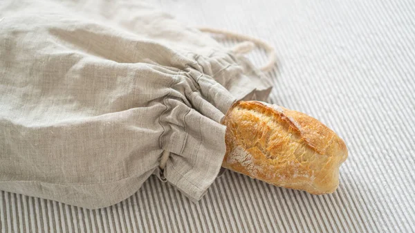 Artisanal ciabatta, güzel bir masa örtüsüyle süslenmiş ahşap bir masanın üzerinde sürdürülebilir bir keten çantada sergileniyordu. Lezzetli İtalyan ciabatta 'sı beyaz bir arka planda sergileniyor..