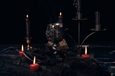 Mumlar, sihirli kitap ve pentagram sembollü cadılık kompozisyonu. Şeytani ayinler için sunak. Kara büyü ve okült nesneler