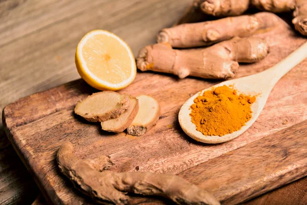 Ahşap zemin üzerinde taze rizom ile ahşap kaşık içinde yakın çekim zerdeçal kaldırma tozu