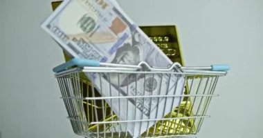 Buying gold. two ingots of 999.9 Fine Gold and dollars rotates in a grocery basket