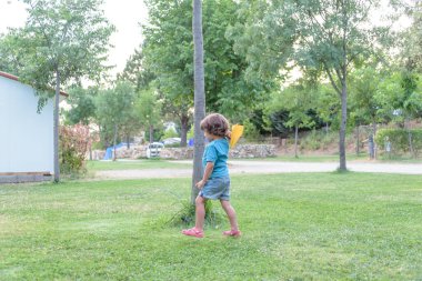 mutlu çocuk eğilerek ve sarı kağıt uçak parlak güneşli bir günde alanında atma.