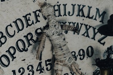 Ouija tahtası, mumlar ve okült hissi uyandıran mistik objelerle karanlık atmosferik bir ortam.
