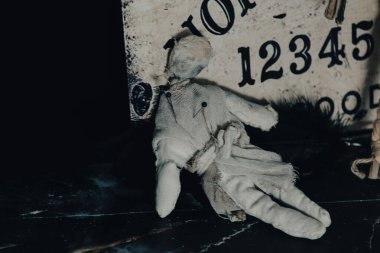 Ouija tahtası, mumlar ve okült hissi uyandıran mistik objelerle karanlık atmosferik bir ortam.