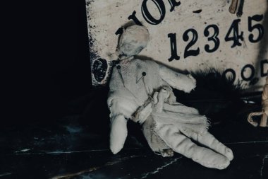 Ouija tahtası, mumlar ve okült hissi uyandıran mistik objelerle karanlık atmosferik bir ortam.