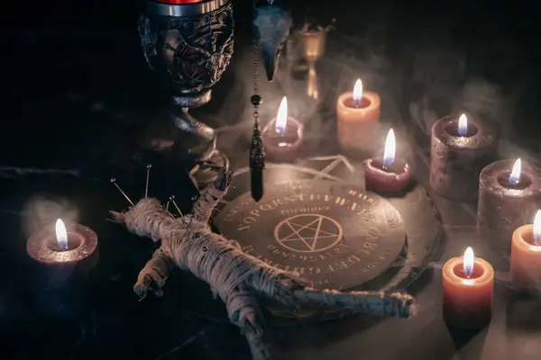 stock image A chilling scene of an occult ritual featuring a voodoo doll pinned with needles, surrounded by candles, a pentagram, and eerie smoke