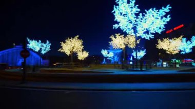 Gece çekimleri, Madrid şehir merkezindeki Atocha Meydanı 'ndan uzaklaşıyor. Ağaçlar Noel ışıklarıyla süslenmiş.
