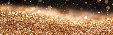 A shimmering surface of golden glitter with a soft focus background clipart