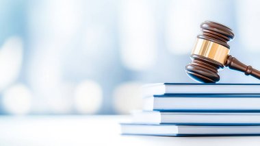 A close-up of a gavel resting on stacked books, symbolizing justice, law, and legal proceedings in a bright, blurred background. clipart