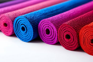 Colorful yoga mats rolled up in vibrant shades of blue, pink, and red, showcasing texture and style for fitness and relaxation needs. clipart