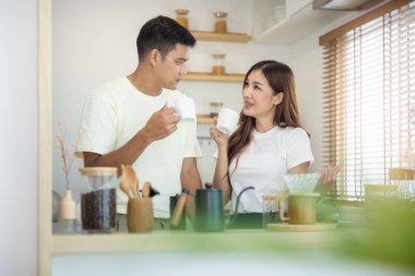 Yapılacak iki kişi ya da sevgili, sabah evde, mutfakta birlikte kahve içecekler. Kahve fincanı ya da kupa, kör ve pencereden yansıyan ışık da dahil. Yaşam tarzı, aşk, mutluluk, aile, ilişki kavramı.