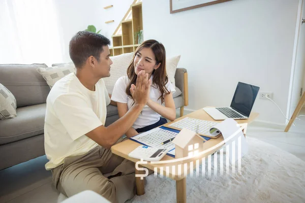 Asian couple in home or house. Include increasing graph, laptop, calculator and document on table. Concept for marriage, family, house value, market price, loan, finance, real estate and property.