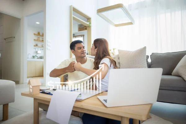 Asian couple in home or house. Include increasing graph, laptop, calculator and document on table. To bump punch with concept for market price, house value, loan, finance, real estate and property.
