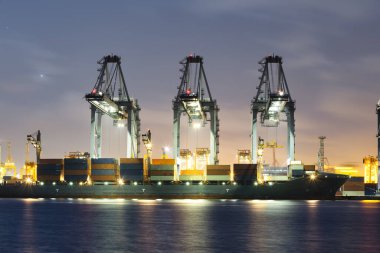 Cargo ship at dock, port or harbor. To loading cargo container, work with crane. Concept of business and industry i.e. shipping, logistics, international trade, freight transport and import export.