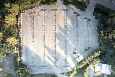 Hava manzaralı ya da manzaralı bir otopark. Açık havada beton kaldırım zeminindeki boş alan, sıra sıra park yeri, çizgi işareti ve aydınlatmayı içeriyor. Havaalanı dışında yer, alışveriş merkezi, araç.