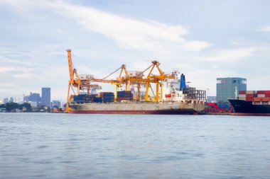 Cargo ship at dock, port or harbor. To loading cargo container, work with crane. Concept of business and industry i.e. shipping, logistics, international trade, freight transport and import export.