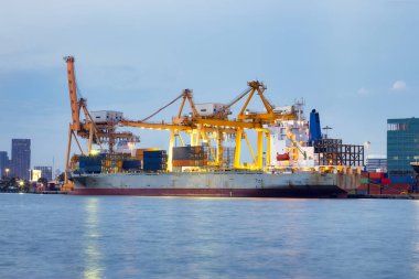 Cargo ship at dock, port or harbor. To loading cargo container, work with crane. Concept of business and industry i.e. shipping, logistics, international trade, freight transport and import export.