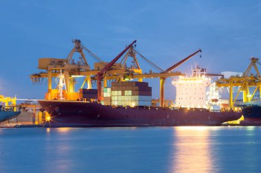 Cargo ship at dock, port or harbor. To loading cargo container, work with crane. Concept of business and industry i.e. shipping, logistics, international trade, freight transport and import export.