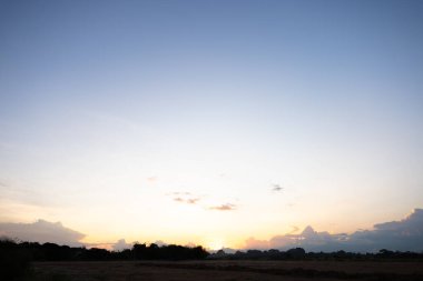 Gökyüzü çok güzel ve bulutlu. Manzara uzay, doğanın ışığı, gün batımı, gün doğumu, ufuk çizgisi veya ufuk çizgisi içerir. Sonbaharda arka plan ve duvar kağıtları için sarı, turuncu ve mavi renkte..
