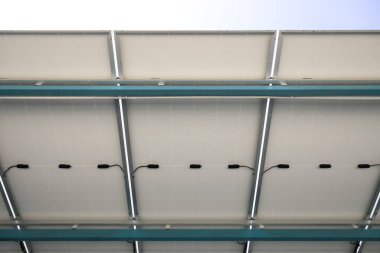 Güneşli araba parkı ya da açık hava otoparkı. Çatı örtüsü ya da güneş panelinden yapılan inşaat. Işıktan elektrik üretmek için icat sistemi teknolojisi. Yeşil temiz enerji kavramı.