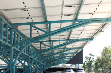 Güneşli araba parkı ya da açık hava otoparkı. Çatı örtüsü ya da güneş panelinden yapılan inşaat. Işıktan elektrik üretmek için icat sistemi teknolojisi. Yeşil temiz enerji kavramı.