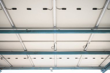 Güneşli araba parkı ya da açık hava otoparkı. Çatı örtüsü ya da güneş panelinden yapılan inşaat. Işıktan elektrik üretmek için icat sistemi teknolojisi. Yeşil temiz enerji kavramı.