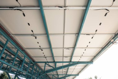 Güneşli araba parkı ya da açık hava otoparkı. Çatı örtüsü ya da güneş panelinden yapılan inşaat. Işıktan elektrik üretmek için icat sistemi teknolojisi. Yeşil temiz enerji kavramı.