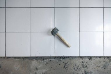 Döşeme döşemesi iç tarafta yapım aşamasında. Tokmak, beton harç çimento ve beyaz kare seramik fayans dahil. Banyo, mutfak ve duş odasında dekor yüzeyi için tamamlayıcı malzeme.