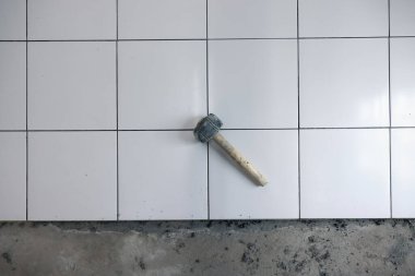 Döşeme döşemesi iç tarafta yapım aşamasında. Tokmak, beton harç çimento ve beyaz kare seramik fayans dahil. Banyo, mutfak ve duş odasında dekor yüzeyi için tamamlayıcı malzeme.
