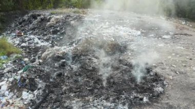 Çöp, yangın ve çöp sahasında duman. Aynı zamanda çöp, çöp, çöp de deniyor. Yanma, ısı ve alevle yıkım. Çevreye etki eder. Hava kirliliği, toksik, felaket ve küresel ısınma