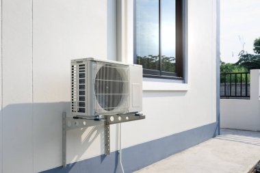 Condenser unit or compressor outside home or residential building. Unit of central air conditioner AC or heating ventilation air conditioning system HVAC. Electric fan and refrigerant pump inside. clipart