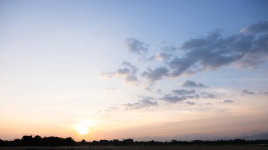 Gökyüzü çok güzel ve bulutlu. Manzara uzay, doğanın ışığı, gün batımı, gün doğumu, ufuk çizgisi veya ufuk çizgisi içerir. Sonbaharda arka plan ve duvar kağıtları için sarı, turuncu ve mavi renkte..