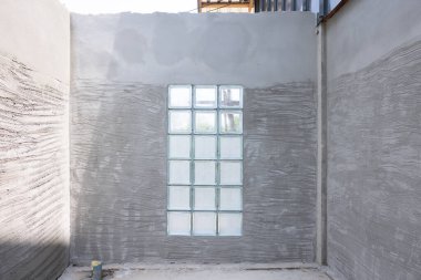 Beton duvar sıva ve kabataslak yüzey ya da inşaat halindeki tuvaletteki fayansları onarmak için tırnak dokusu. Işık için şeffaf cam blok duvar ekle.