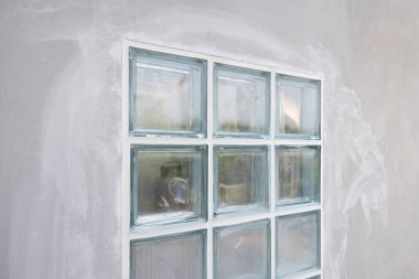 İnşaat halindeki beton duvardaki şeffaf cam bloğu kapatın. Sınırdaki cam bloğun kenarına dolgu macunu sürmek için. Işık için inşaat malzemesi içeri girer..