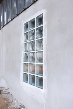 İnşaat halindeki beton duvarda şeffaf cam bloklar olan dış görünüş binası. Yivli kenarda dolgu macunu sürmek için. Işık için inşaat malzemesi içeri girer..