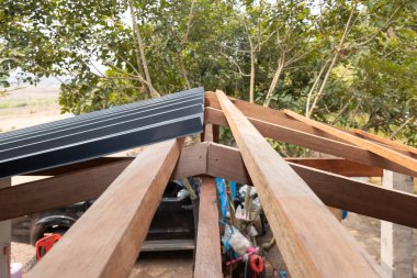 Bakış açısına göre inşaat halindeki çatı, ev binasını kaplayan kahverengi ahşap çerçeve yapısı hem çatı katı hem de gri metal levhadan oluşuyor. Kanalizasyon suyu için eğim yüklemek.