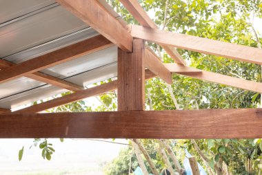 İnşaat halindeki çatı katındaki ahşap bağlantı yeri King post, ridge, kiriş, purlin ve metal levhadan oluşuyor. Ahşap işçilikli ev inşaatı.