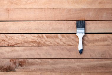 Boya fırçası kereste yığınına vernik uygular, ahşap ürünü de yatay bileşime. İnşaat konsepti için daha koyu kahverengi görünüm, koruyucu veya kaplama leke yüzey giysisi.