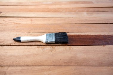 Boya fırçası yeni kereste yüzeyine vernik uyguluyor. Yatay bileşim olarak ahşap ürün. Islak, zarif ve koyu kahverengi renkte görünün. Artırmak, korumak ya da kaplamak için..