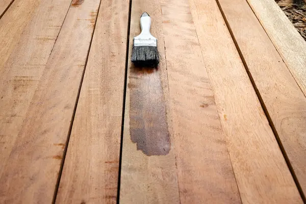 Boya fırçası kereste ahşap perspektif görünümlü vernik kimyasal ürün uygulayın. Tahtakurusu, termit ve mantarı önlemek için parlak ve koyu kahverengi renge bakın..