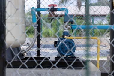 Su pompası istasyonu. PVC borusuna elektrik pompası bağlantısı, valf kontrolü ve basınç tankı. Zincir halkayla. Su akışı, kamu hizmeti, su arıtma ve su tesisatı için makine ekipmanı.