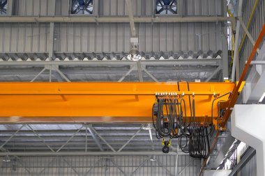 Fabrikada ya da depoda vinç var. Üretim ve kargo taşımacılığı için kiriş yapının üzerinde vinç, kanca ve tel halat ile endüstriyel makine veya kaldırma ekipmanları.