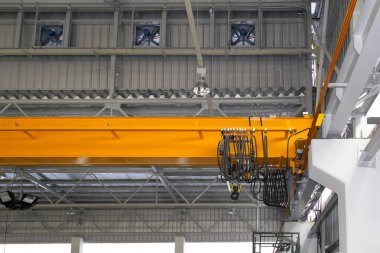 Fabrikada ya da depoda vinç var. Endüstriyel makine ya da kaldırma ekipmanları kiriş kiriş yapısına ip ve kanca ile bağlandı. Havalandırma vantilatörünü serinlik ve hava akımı için yan duvara yerleştir.