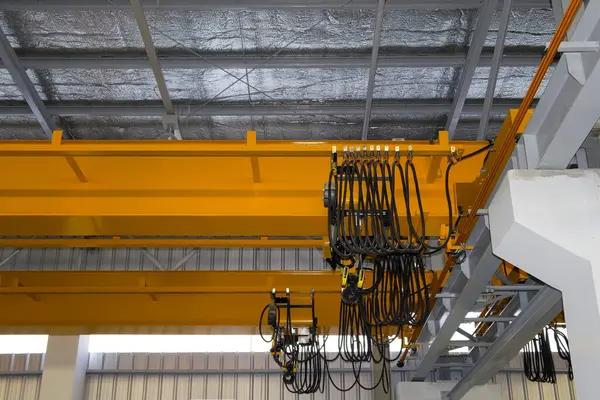 Fabrikada ya da depoda vinç var. Üretim ve kargo taşımacılığı için kiriş yapının üzerinde vinç, kanca ve tel halat ile endüstriyel makine veya kaldırma ekipmanları.