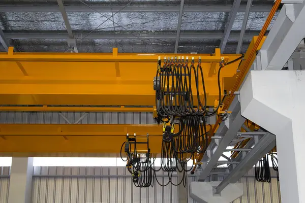 Fabrikada ya da depoda vinç var. Üretim ve kargo taşımacılığı için kiriş yapının üzerinde vinç, kanca ve tel halat ile endüstriyel makine veya kaldırma ekipmanları.
