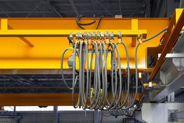 Fabrikada ya da depoda vinç var. Üretim ve kargo taşımacılığı için kiriş yapının üzerinde vinç, kanca ve tel halat ile endüstriyel makine veya kaldırma ekipmanları.