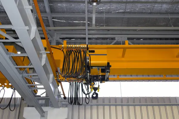 Fabrikada ya da depoda vinç var. Üretim ve kargo taşımacılığı için kiriş yapının üzerinde vinç, kanca ve tel halat ile endüstriyel makine veya kaldırma ekipmanları.