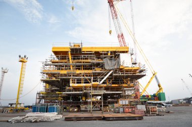 Sürüngen vinç tarafından kıyıda petrol kuyusu inşaatı. Enerji yakıtları yatırımlarında ham petrol arama ve sondajı için ağır sanayi ve mühendislik teknolojisi.