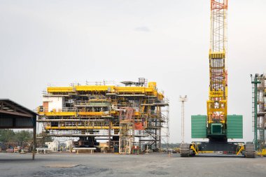 Kıyıda inşaat halindeki petrol kulesi. Çelik yapı platformunu büyük vinç kaldırma, sürüngen vinç ya da derrick vinç ile birleştirmek için. Kaba ve doğal gaz arama ve sondaj için ağır sanayi.